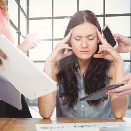 Stressed woman sitting with hands on forehead in office
