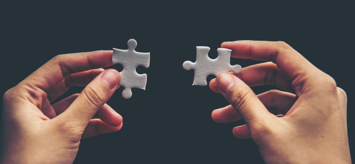 Close up of hand placing the last jigsaw puzzle piece, Hand holding missing jigsaw puzzle piece down in to the place, conceptual of problem solving, finding a solution.
