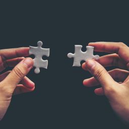 Close up of hand placing the last jigsaw puzzle piece, Hand holding missing jigsaw puzzle piece down in to the place, conceptual of problem solving, finding a solution.