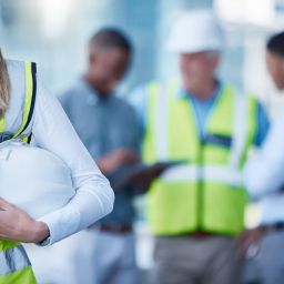 Architecture, planning and woman with helmet in blurred office for project management, teamwork and inspection. Civil engineering, collaboration and contractor at construction site with safety gear.